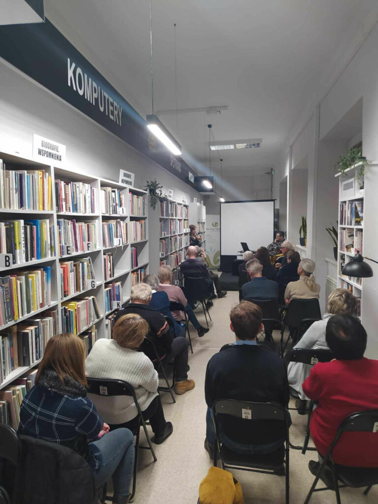 Na zdjęciu na krzesłach siedzą osoby przybyłe na spotkanie z Tomaszem Walczykiem