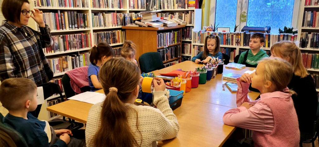 na zdjęciu widać sale biblioteczną i siedzące przy stole dzieci