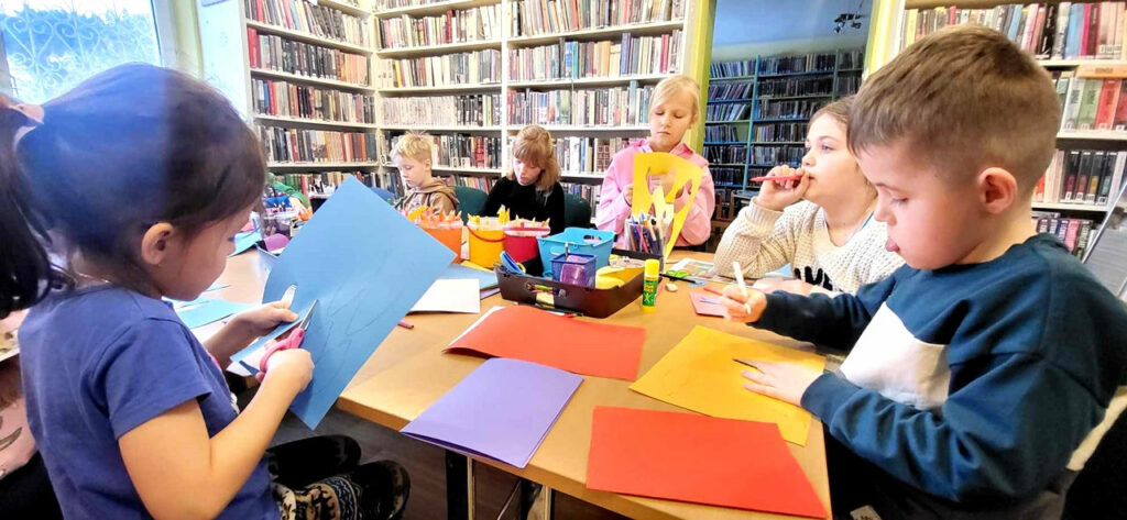 na zdjęciu widać sale biblioteczną i siedzące przy stole dzieci