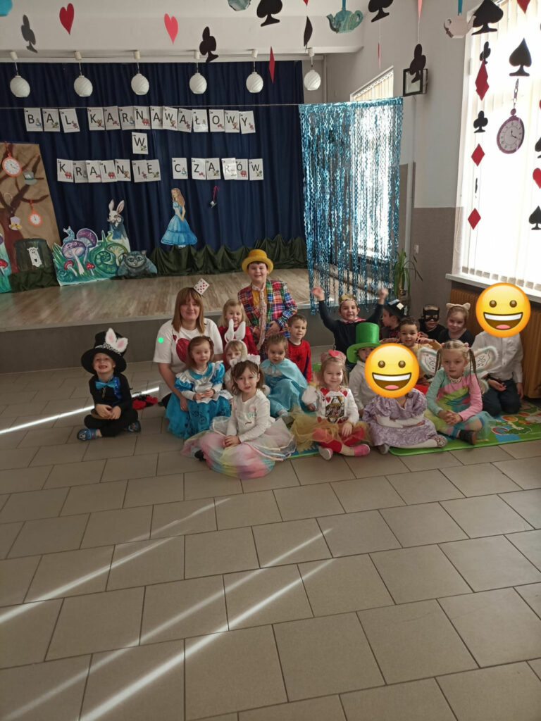Na zdjęciu widoczna jest grupa przedszkolaków i pani wychowawczyni pozujących do wspólnego zdjęcia. W tle dekoracje tematyczne.