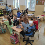 na zdjęciu widać salę szkolną, dzieci siedzą przy stolikach, biorą udział w zabawie