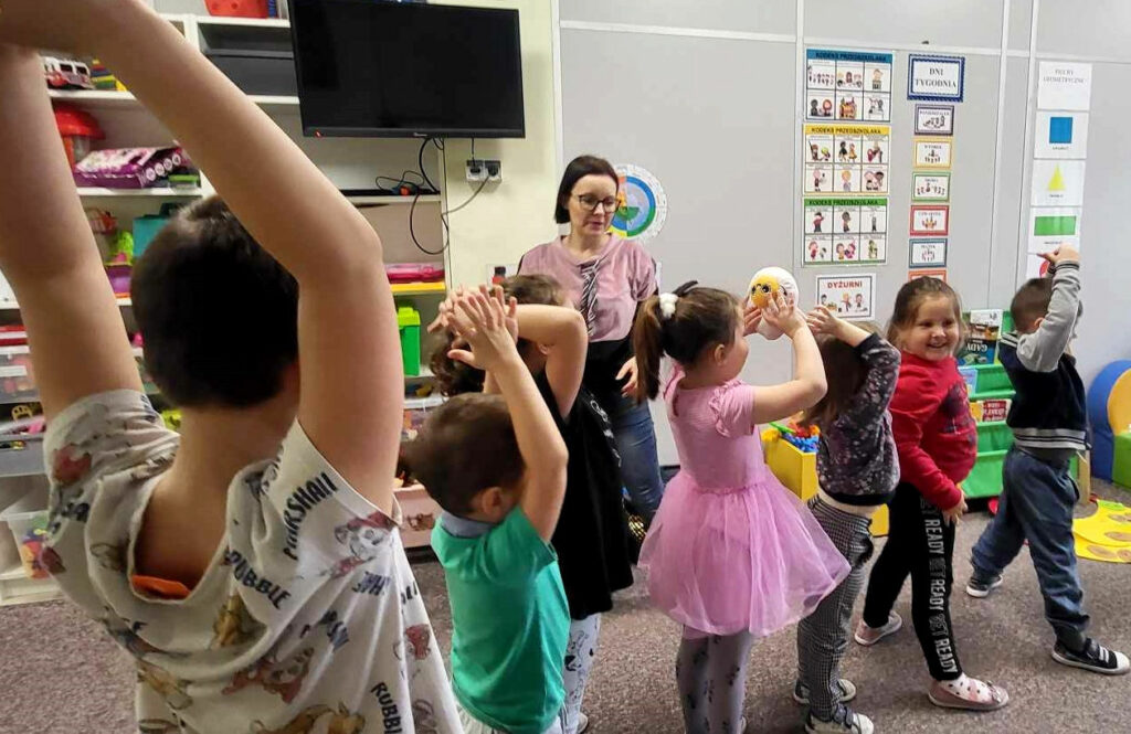 na zdjęciu widać dzieci w wieku przedszkolnym stojące w szeregu