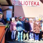 na zdjęciu widać dzieci stojące przed biblioteką