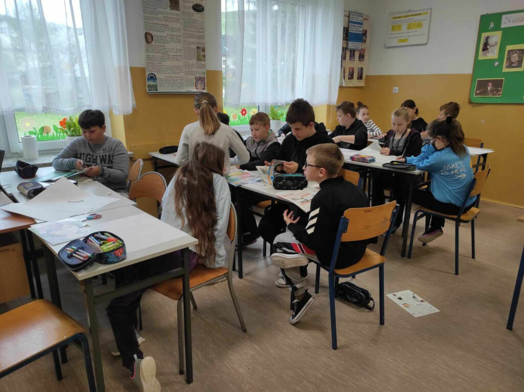 na zdjęciu widać salę szkolną, dzieci wykonują prace