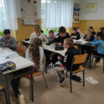 na zdjęciu widać salę szkolną, dzieci wykonują prace