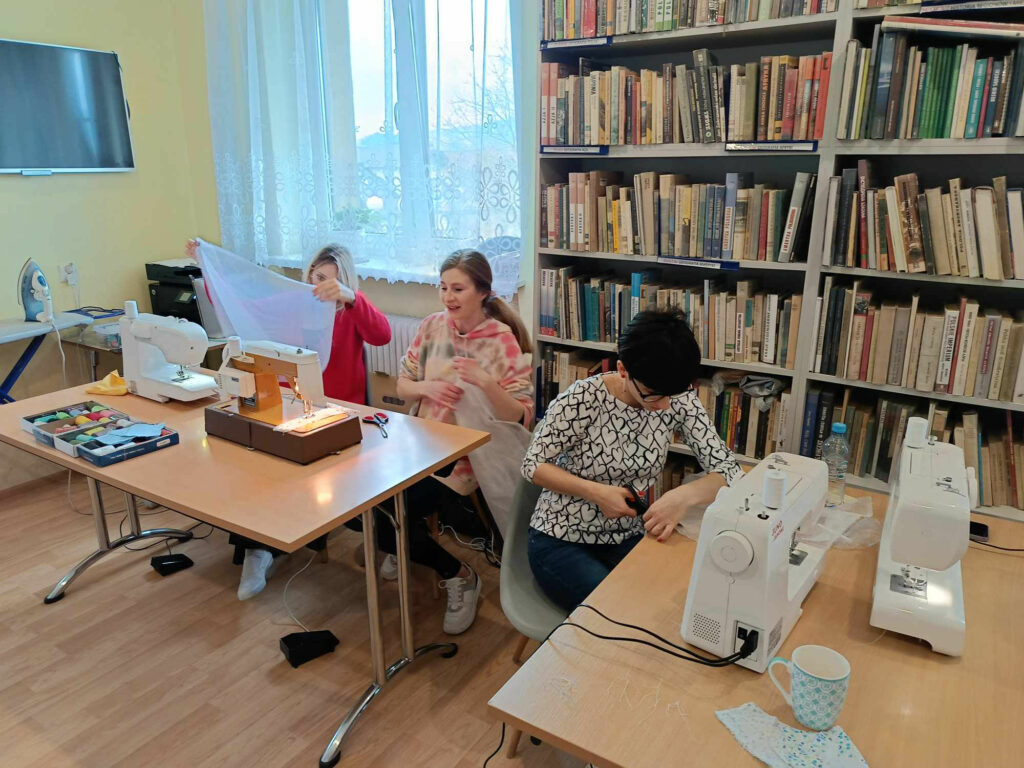 Przy stołach z maszynami do szycia panie uczestniczące w warsztatach