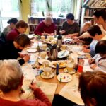 na zdjęciu widać panie seniorki siedzące przy stole i malujące w sali bibliotecznej