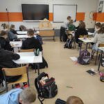 na zdjęciu widać salę szkolną, uczniowie siedzą przy stolikach, wykonują prace
