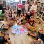 na zdjęciu widać dzieci siedzące na podłodze w sali bibliotecznej