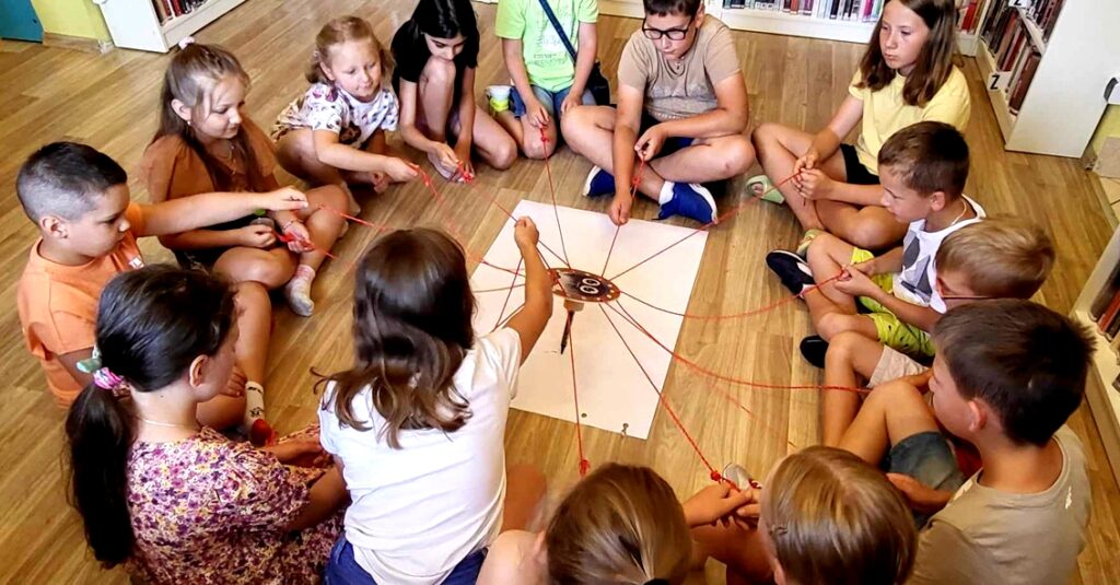 na zdjęciu widać dzieci siedzące na podłodze w kole