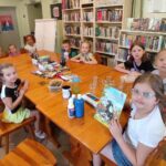 na zdjęciu widać salę biblioteczną, dzieci siedzą przy stole
