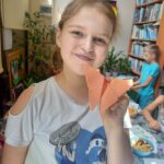 Na zdjęciu dziewczynka prezentuje pracę plastyczną