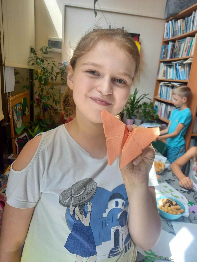 Na zdjęciu dziewczynka prezentuje pracę plastyczną