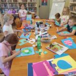 na zdjęciu widać salę biblioteczną, dzieci siedzą przy stole, wykonują zadanie