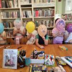 na zdjęciu widać salę biblioteczną, dzieci prezentują swoje nowe balonowe twarze
