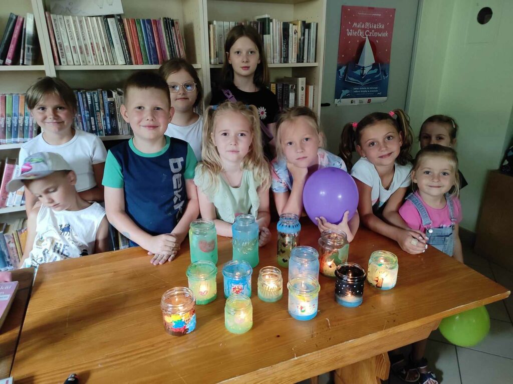 Na zdkęciu dzieci a przed nimi prace plastyczne wykonane prze nie