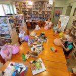 na zdjęciu widać salę biblioteczną, dzieci siedzą przy stole, wykonują prace plastyczne