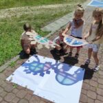 na zdjęciu widać dzieci bawiące się na placu wokół biblioteki