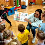 na zdjęciu widać dzieci oraz kobieta pokazującą im książkę