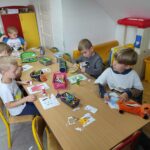 na zdjęciu widać dzieci, siedzą przy stolikach i wykonują pracę plastyczną