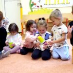 dzieci siedzące na podłodze w sali przedszkolnej
