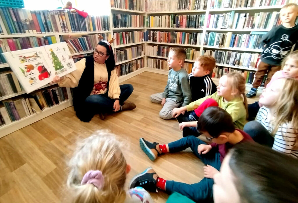 na zdjęciu widać dzieci słuchające czytanej im książki