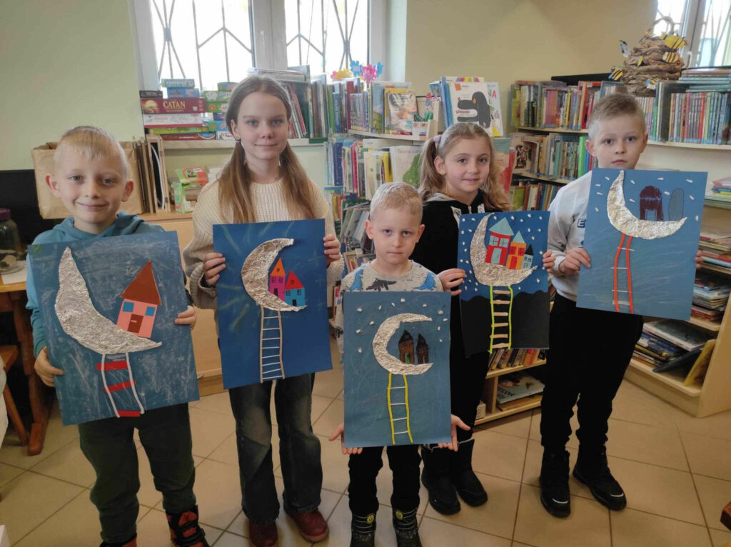 na zdjęciu widać salę biblioteczną, dzieci prezentują wykonane prace