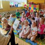 na zdjęciu widać dzieci siedzące na kolorowym dywanie