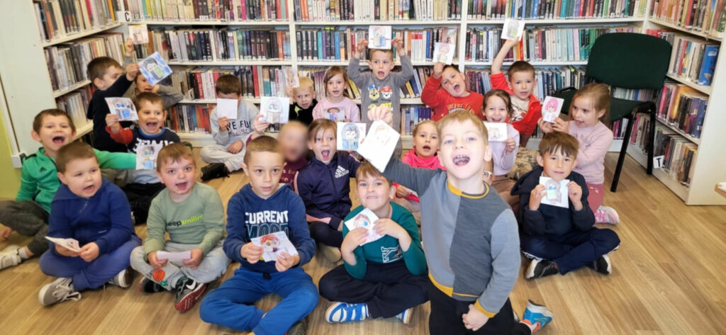na zdjęciu widać dzieci siedzące na podłodze w sali bibliotecznej