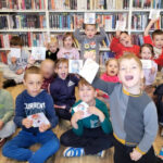 na zdjęciu widać dzieci siedzące na podłodze w sali bibliotecznej