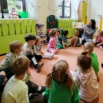 na zdjęciu widać dzieci w sali przedszkolnej siedzące na ziemi