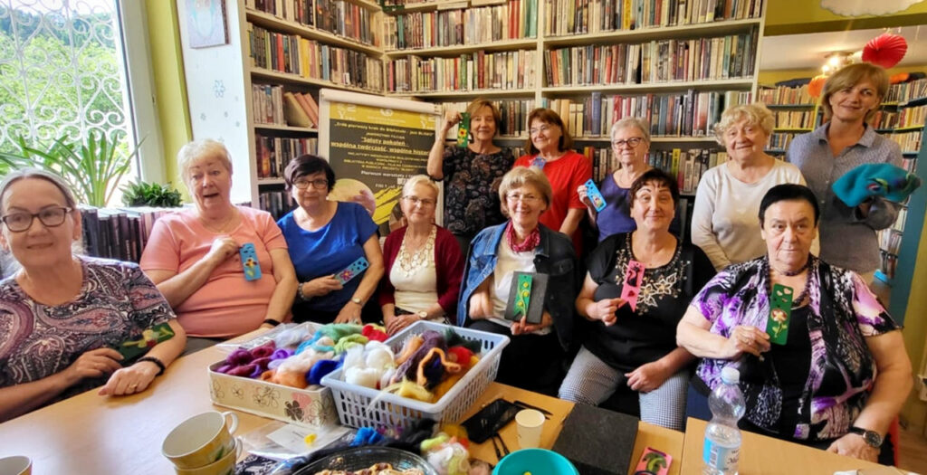 na zdjęciu widać seniorki stojące w sali bibliotecznej na tle książek