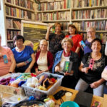 na zdjęciu widać seniorki stojące w sali bibliotecznej na tle książek