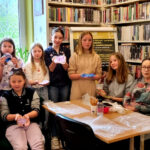 na widać osoby w różnym wieku dzieci i seniorki stojące w sali bibliotecznej