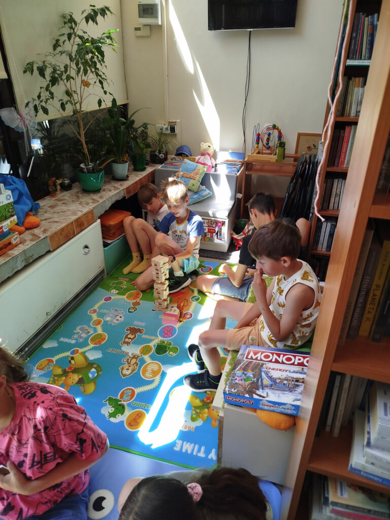 Na zdjęciu widać czterech chłopców którzy siedza na kolorowych matach i układaja klocki.