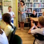 na zdjęciu widać dzieci siedzące przy stole w sali bibliotecznej