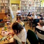 na zdjęciu widać dzieci siedzące przy stole w sali bibliotecznej