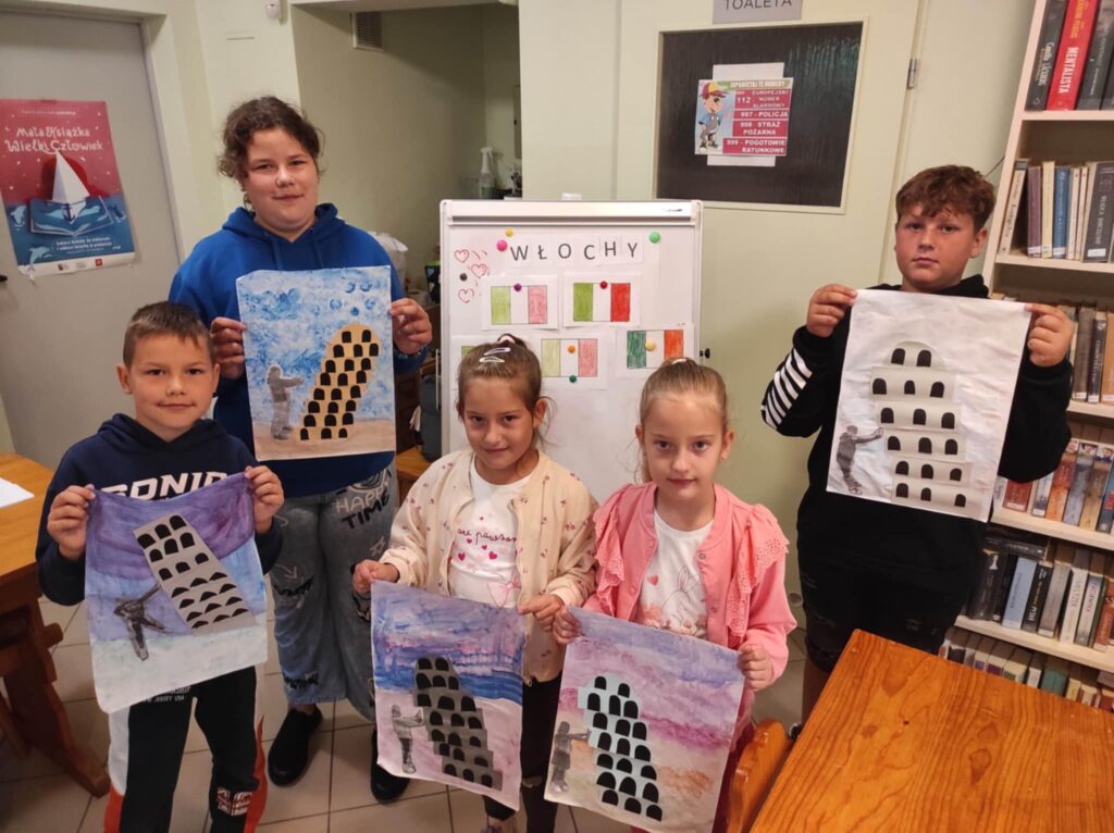 Na zdjęciu trzy diewczynki i dwóch chłopców prezentuja prace plastyczne w sali bibliotecznej. Na ilustracjach włoskie zabytki.