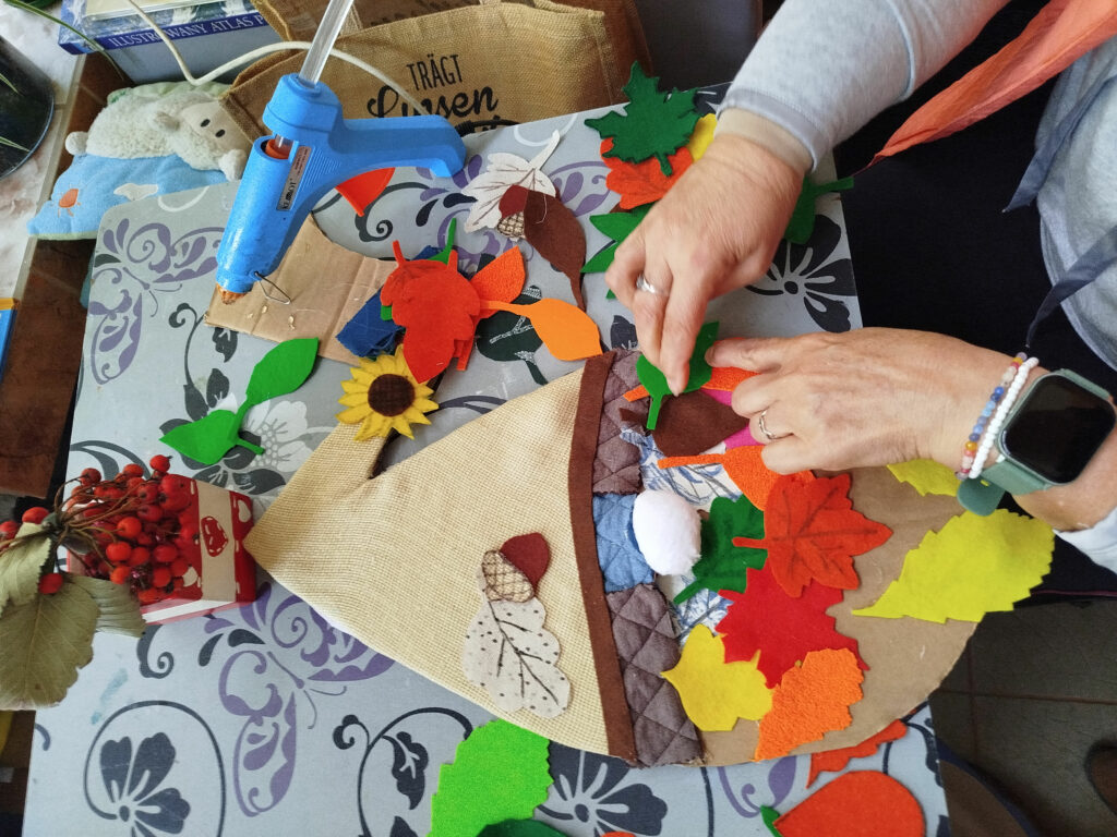 na zdjęciu widać ręce kobiety wykonujące prace plastyczne jesienna dekoracje do biblioteki