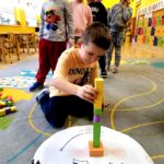 na zdjęciu widać dzieci układające klocki na kolorowym dywanie