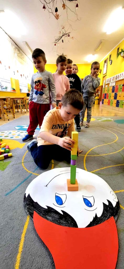 na zdjęciu widać dzieci układające klocki na kolorowym dywanie