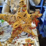 Na zdjęciu częściowo widac kobietę trzymajaca w ręku gwiazde świąteczna ozdobioną jarzębiną.