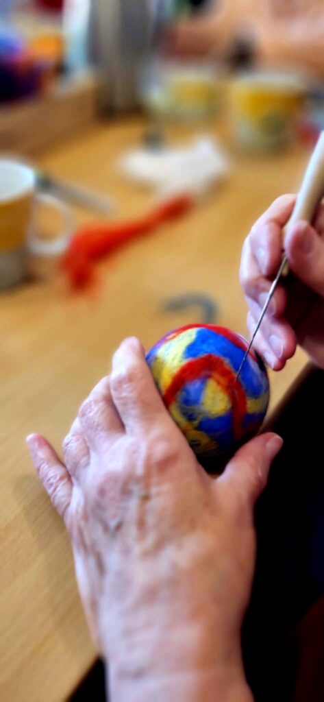 Na zdjęciu widać kolorową bańkę którą wykonuje na zajęciach pani seniorka uczestnicząca w zajęciach bibliotecznych