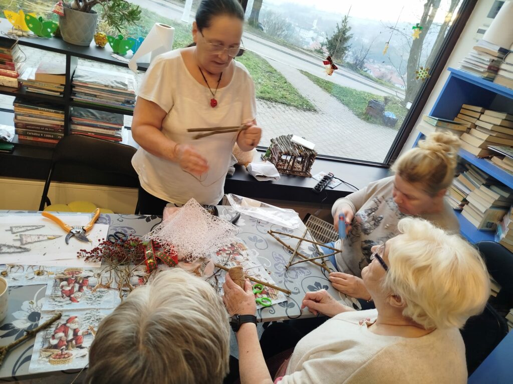 Wokół stołu cztery kobiety - wykonuja prace - ozdoby świąteczne.