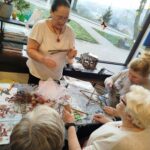 Wokół stołu cztery kobiety - wykonuja prace - ozdoby świąteczne.