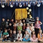 W sali uczestnicy balu andrzejkowego. w tyle za nimi granatowa ściana