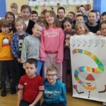 Na zdjęciu duża grupa dzieci w wieku szkolnym 1-3 klasa. Dzieci trzymają w ręku karton na którym jest Bałwan z wymalowanym kolorowym szalikiem .