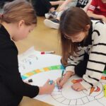 na podłdze widać dwie dziewczynki, które kolorują szalik Bałwana.