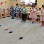 Szóstka przedszkolaków stoi w rzędzie. W rękach trzymają patyczki na których są sznurki i na końcu sznurka jest rybka. Dzieci bawią sie w łowienie rybek.