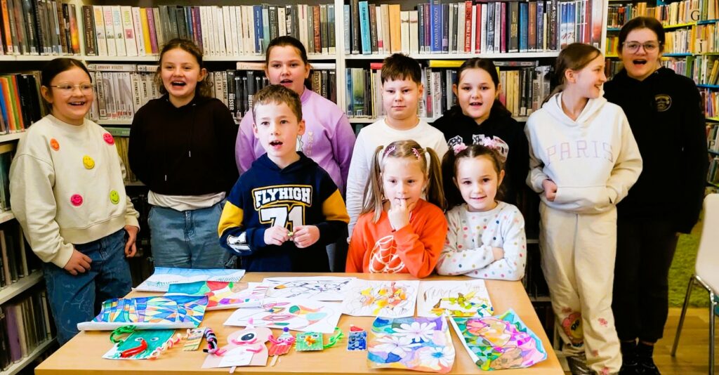 na zdjęciu widać dzieci w sali bibliotecznej na tle regału